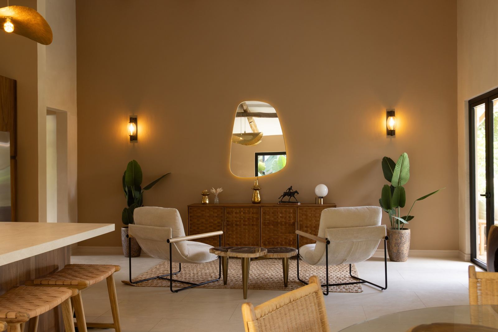 Sala de Casa Bergamota 13: dos sillones claros, aparador de madera tejida y espejo retroiluminado