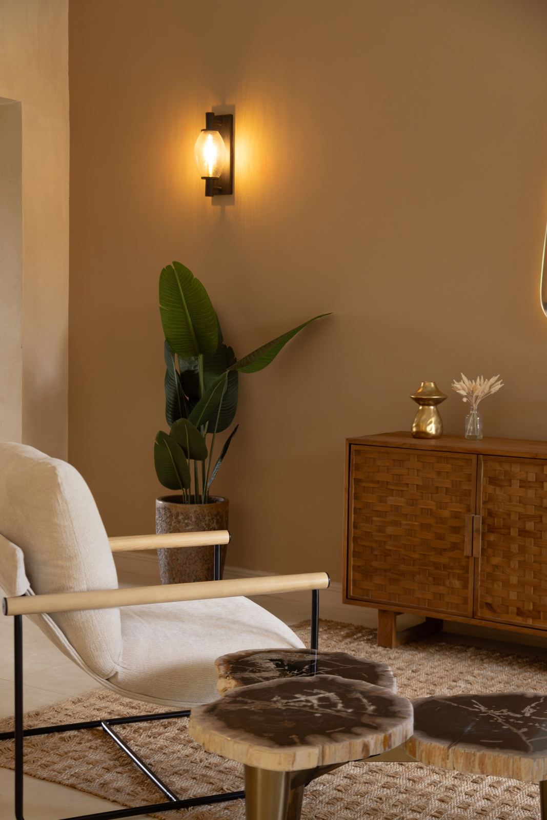 Detalle de la sala: sillón claro, mesa de centro de madera y aplique de pared